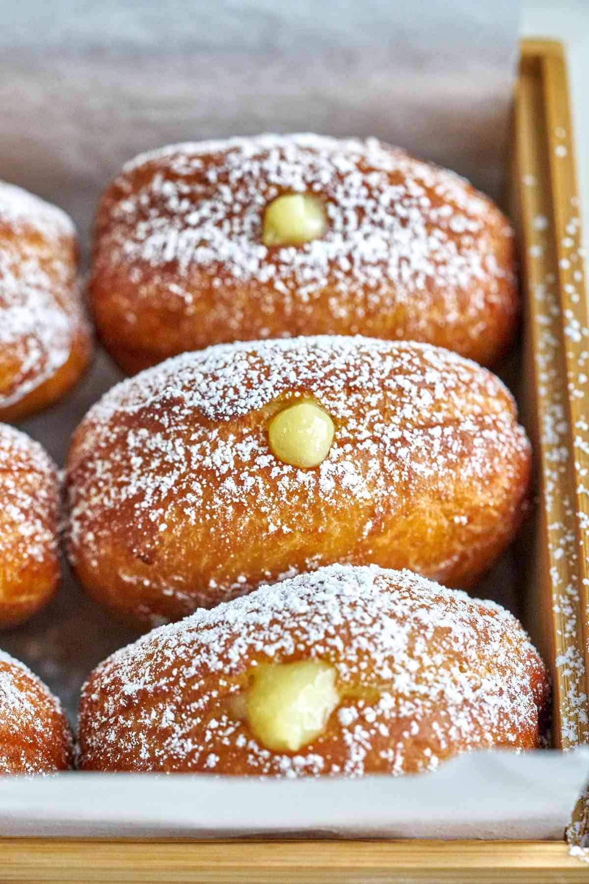 Filled donuts in a wood box.