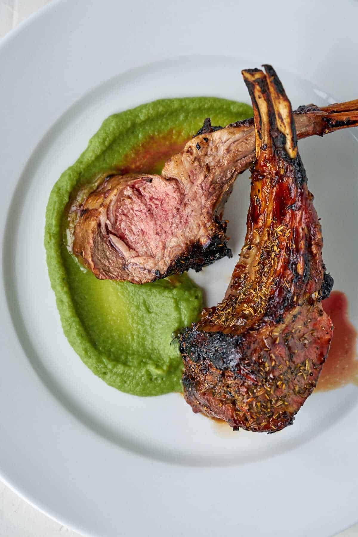 Rack of lamb on a plate with green puree.