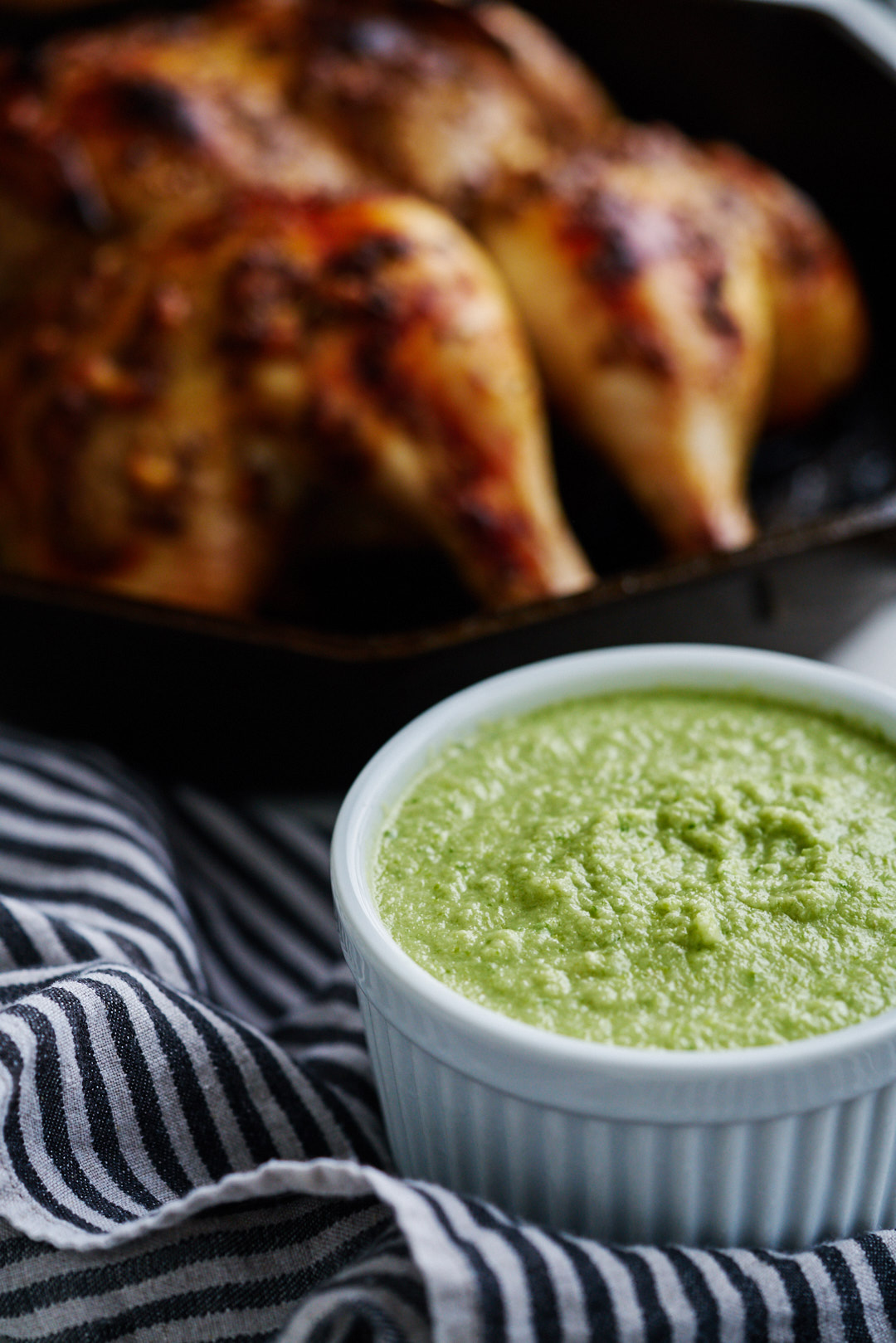 Green dipping sauce next to roasted chicken.