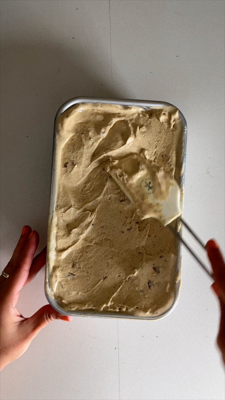 Ice cream being spread in a metal bread loaf pan.
