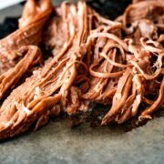 Shredded meat on a black cutting board.