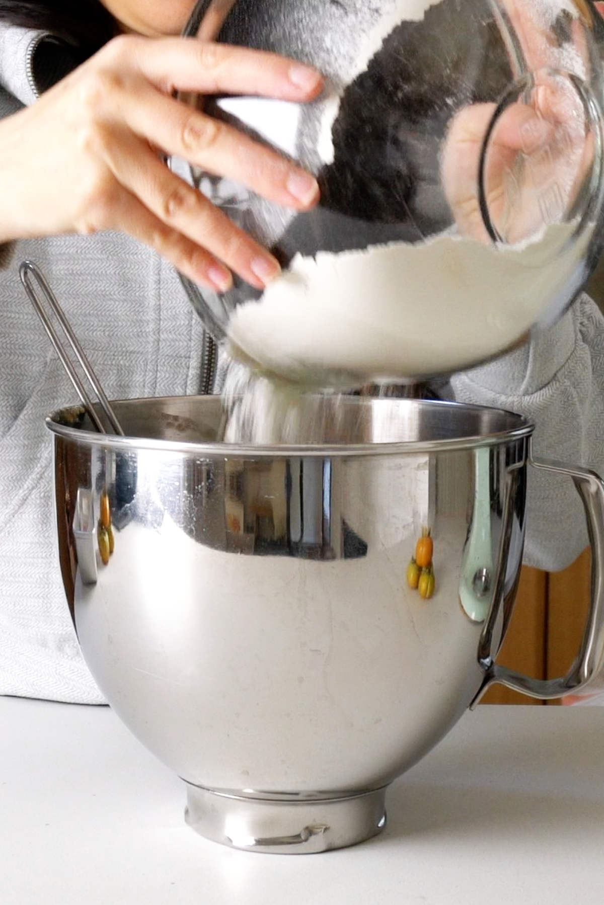 Pouring flour into a metal stand mixer bowl.