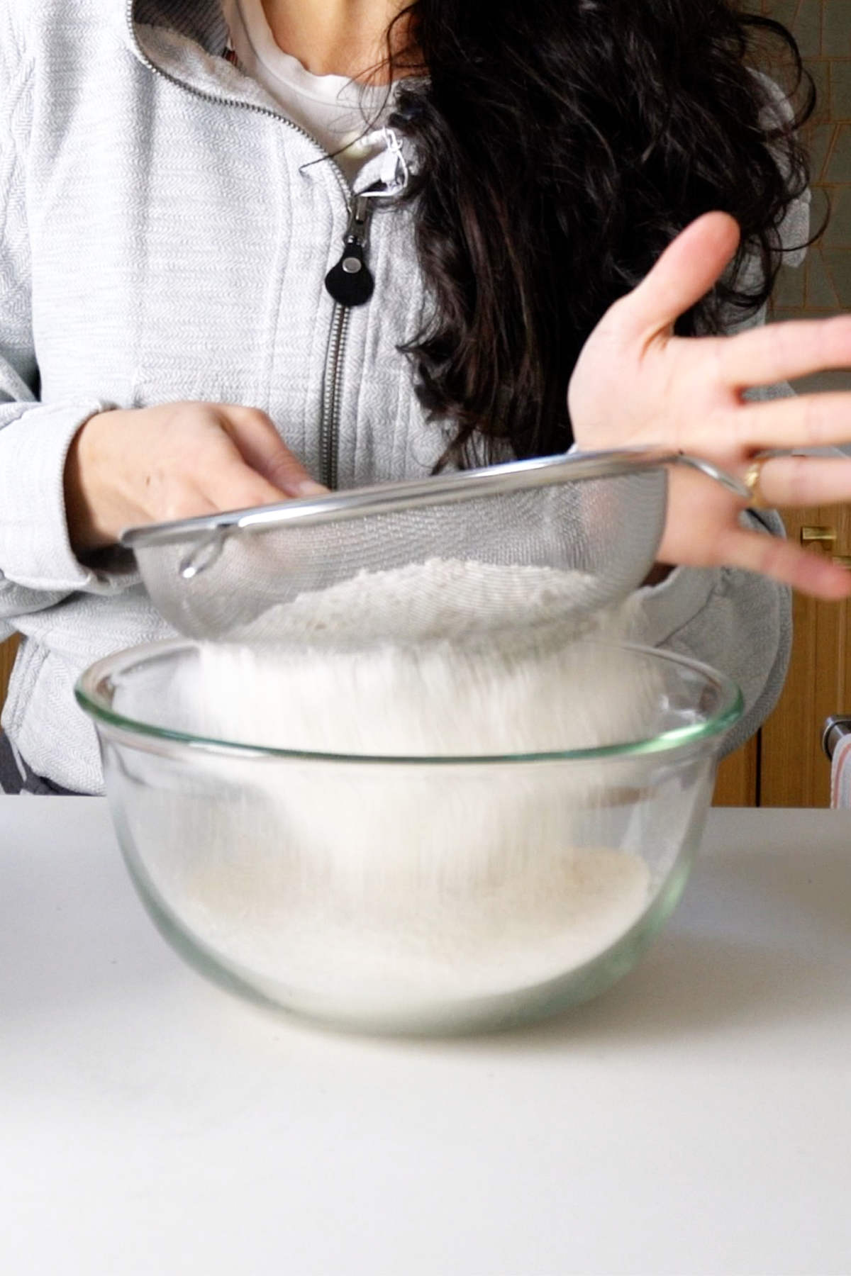 Sifting flour into a glass bowl.