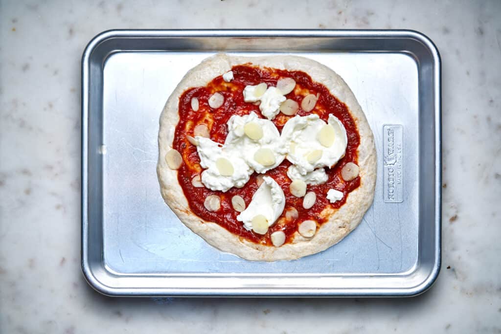 Raw pizza on a baking sheet.