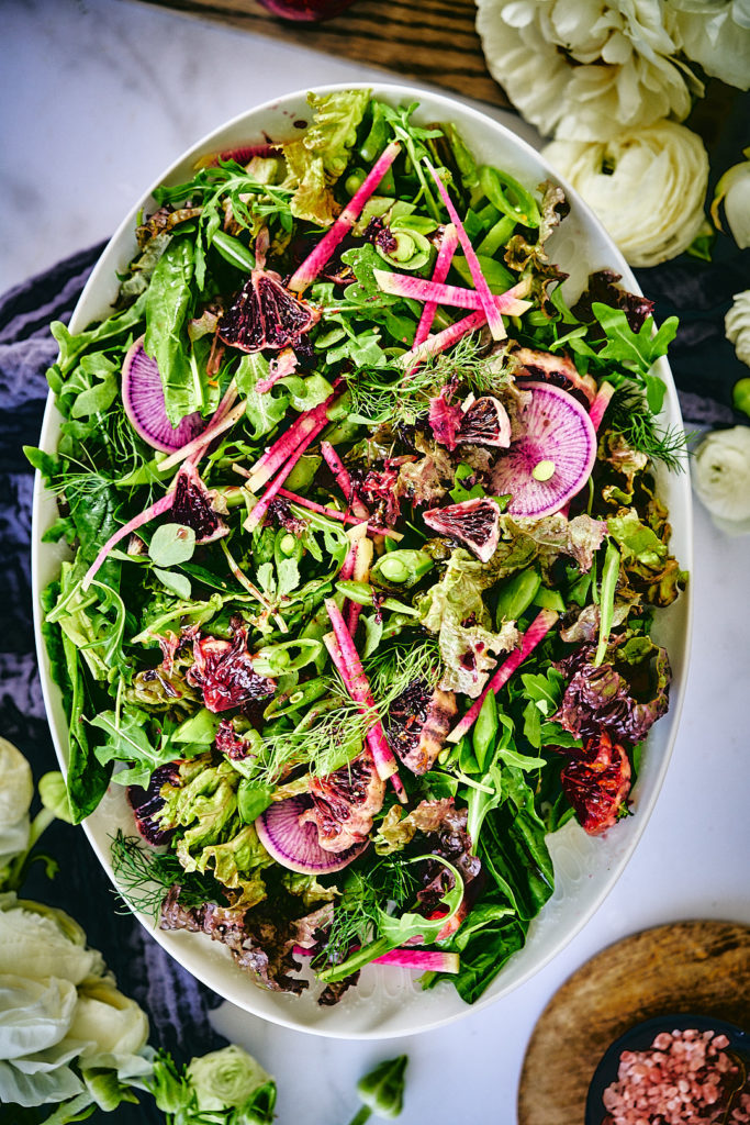 Top view of a salad with herbs, citrus, and radish.