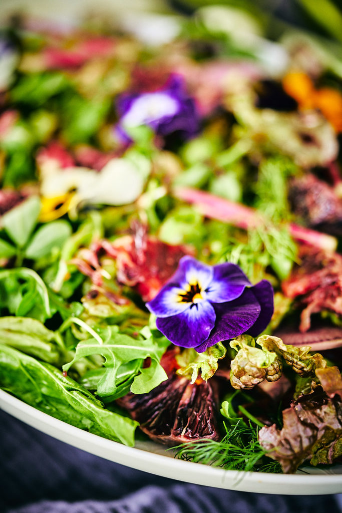 Close up of flowers and herbs on a salad.