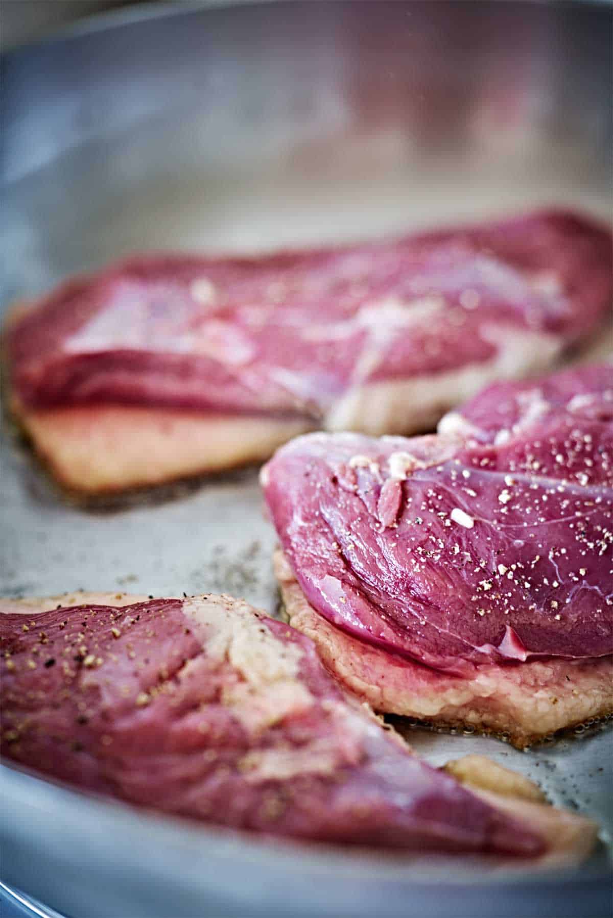 Cooking duck breasts in a pan.