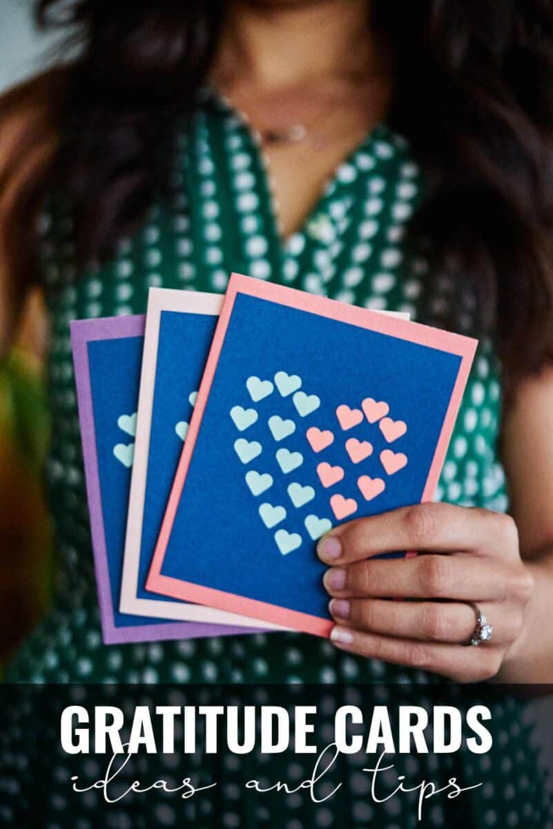 Woman holding three cards with hearts on them.