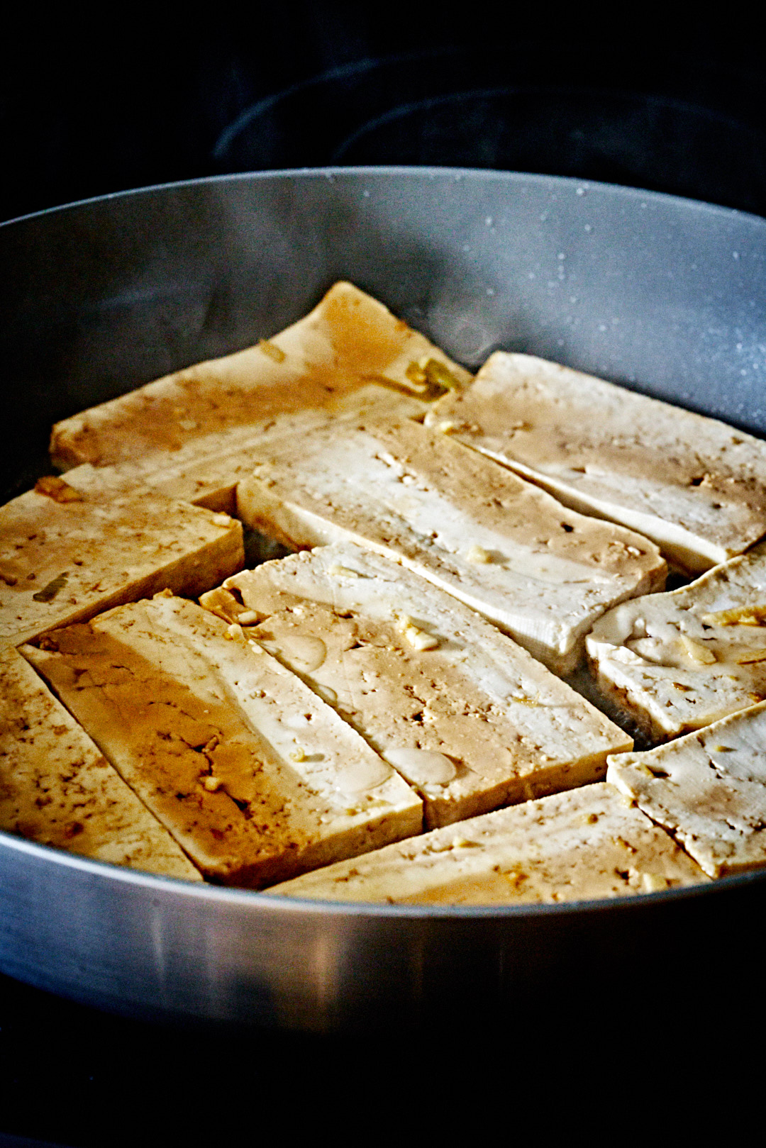 Marinated tofu cooking in a pan.