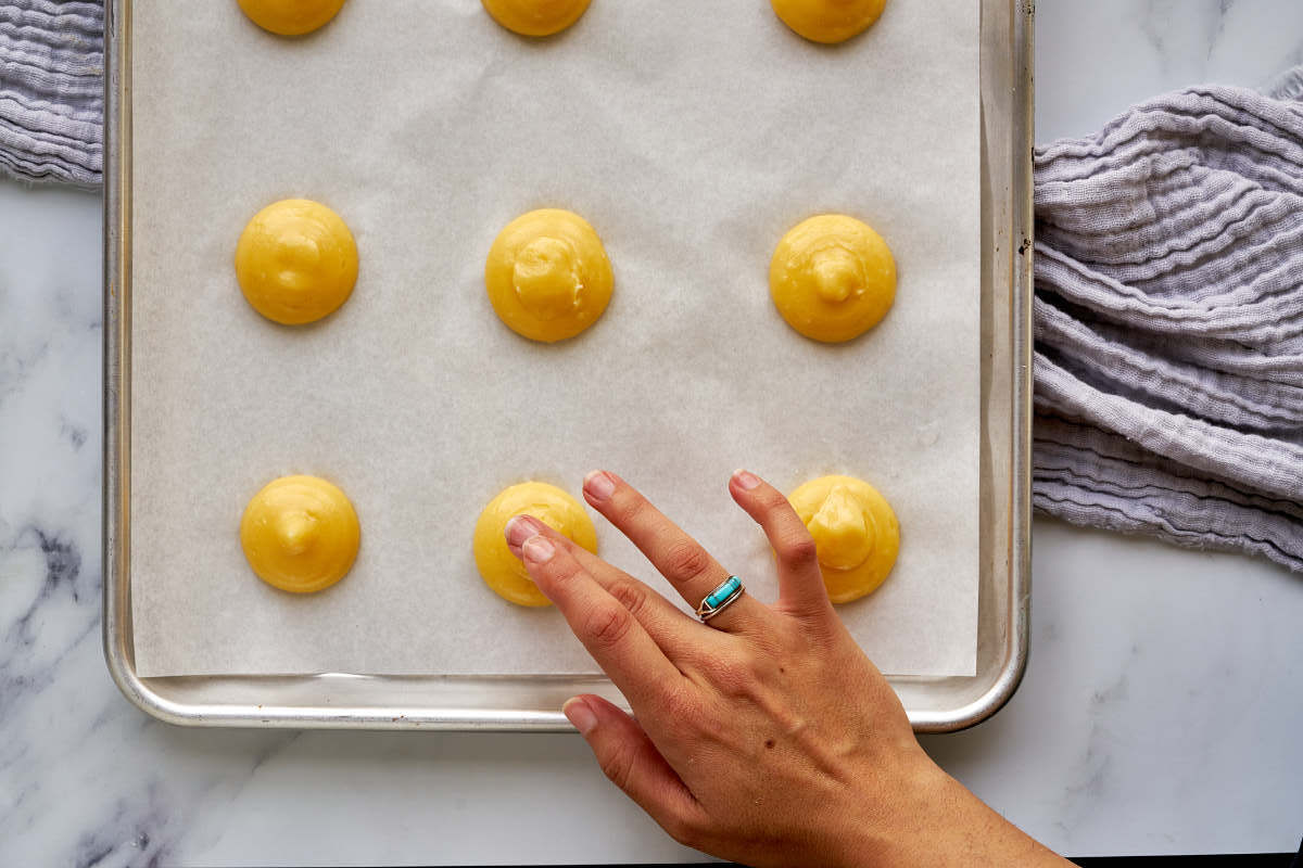 Tapping the top of cream puff dough with wet fingers.