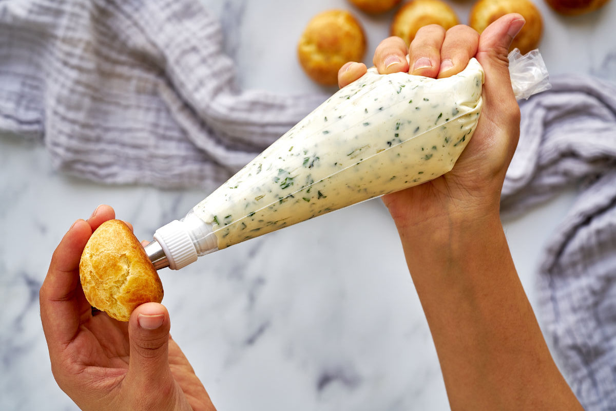 Filling a cream puff with a piping bag.