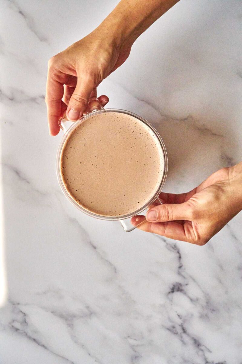 Hands holding a container of nut milk.