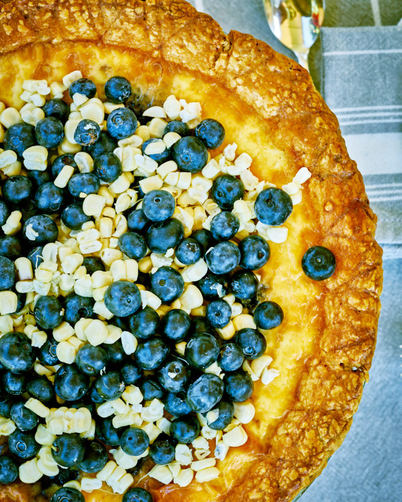 Custard pie flatlay with fresh corn and blueberries.