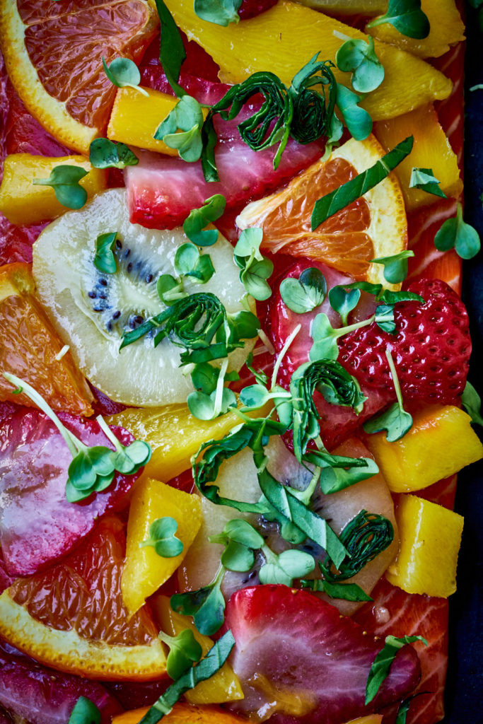 Close up shot of tropical fruit and fresh herbs on salmon filet.