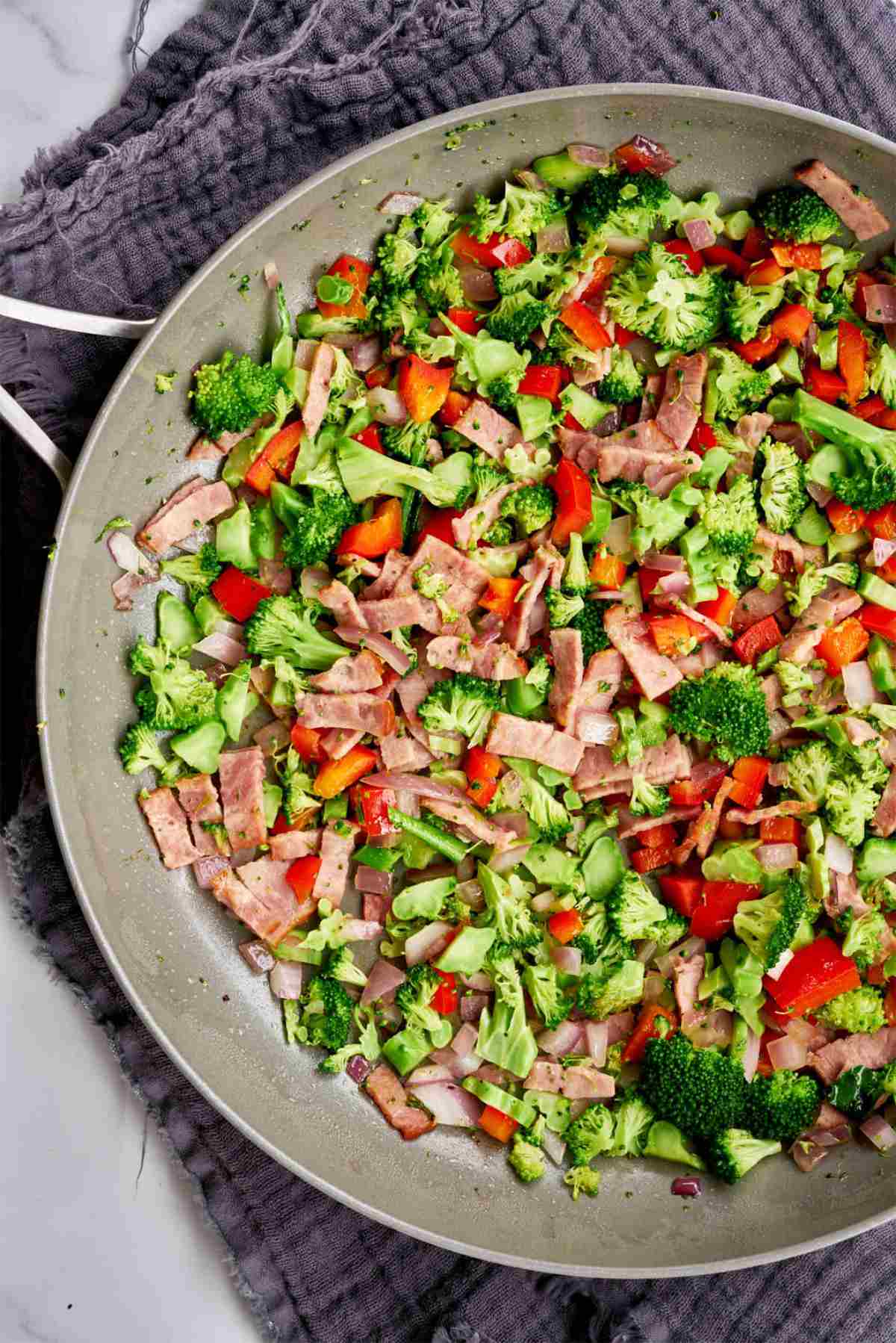 Vegetables and turkey bacon in a pan.