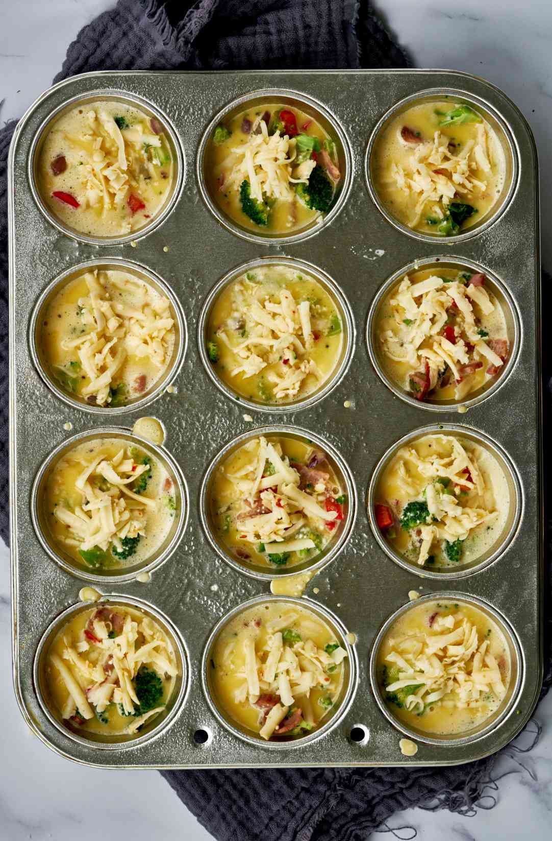 Mini omelettes in a muffin tin ready to bake.