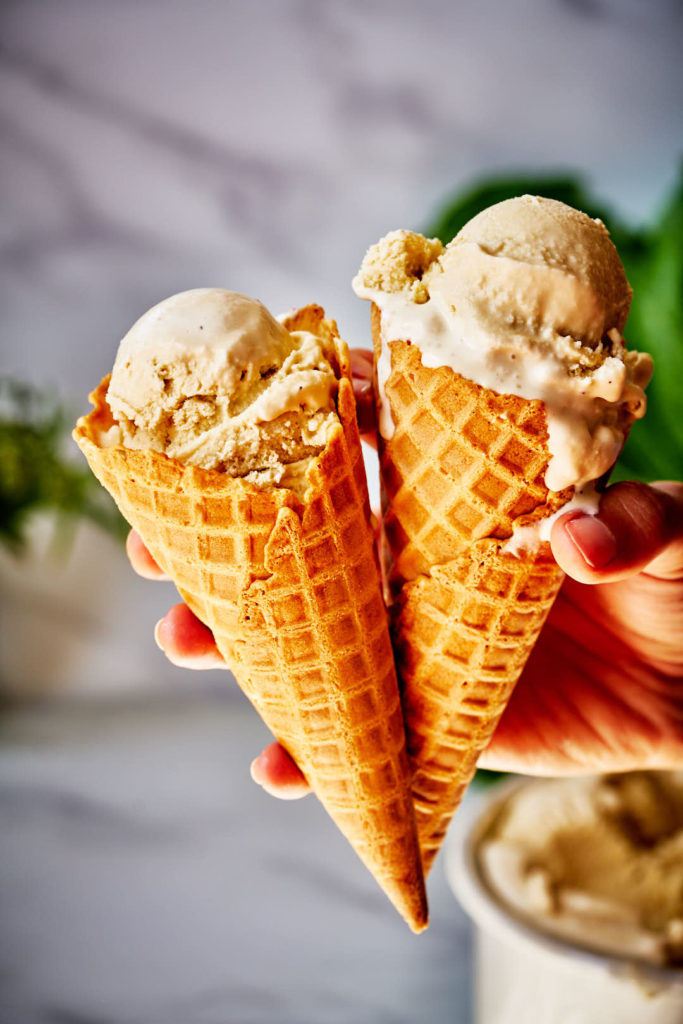 Hand holding two ice cream cones.