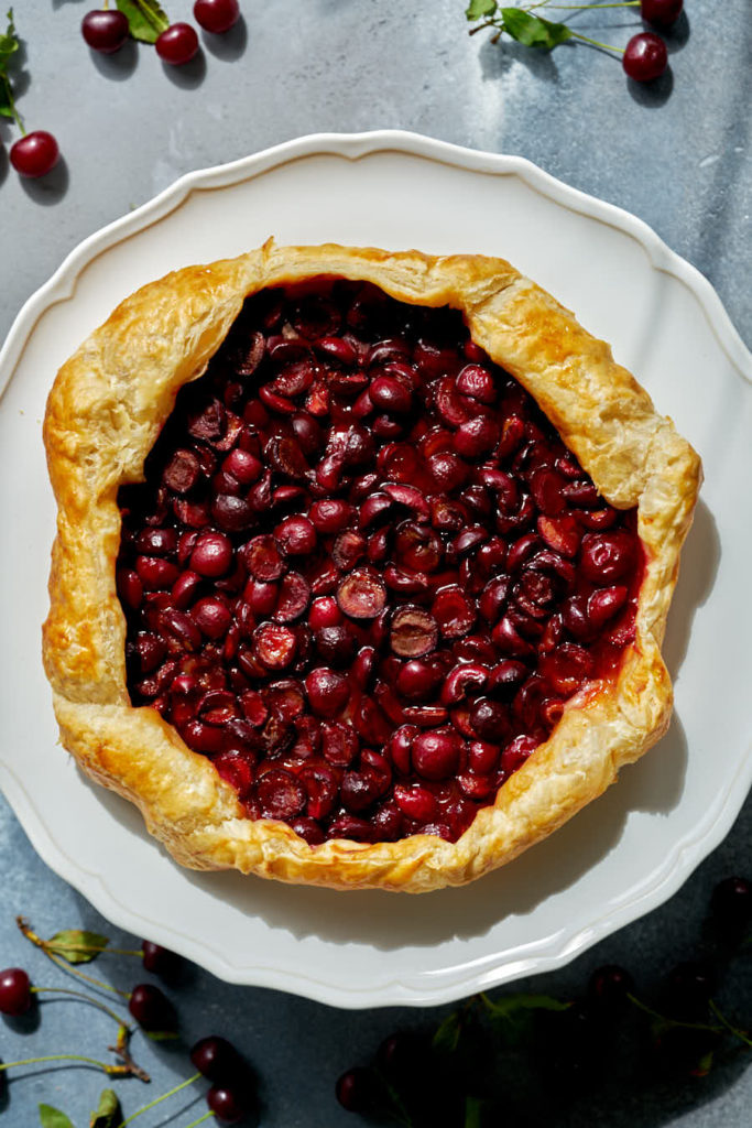 Cherry galette on a white cake stand.