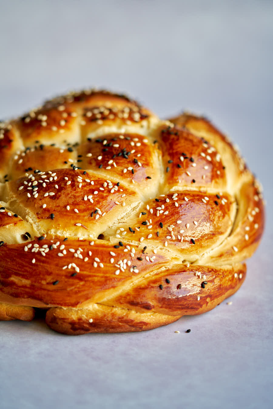 Round challah bread on grey backdrop.