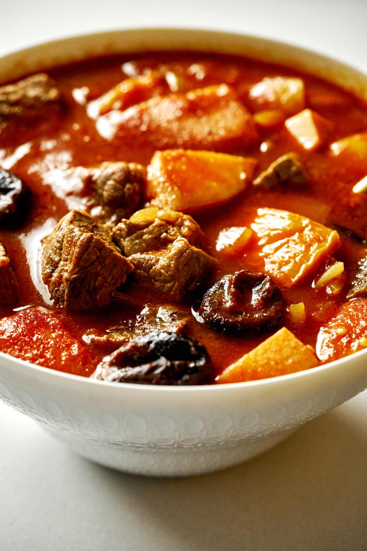 Ceramic two-tone bowl with red quince and beef stew.