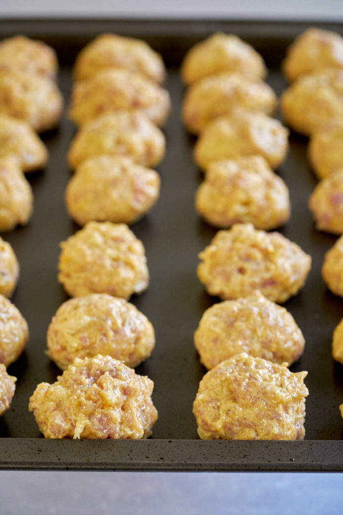 Meatballs lined up on a baking sheet.