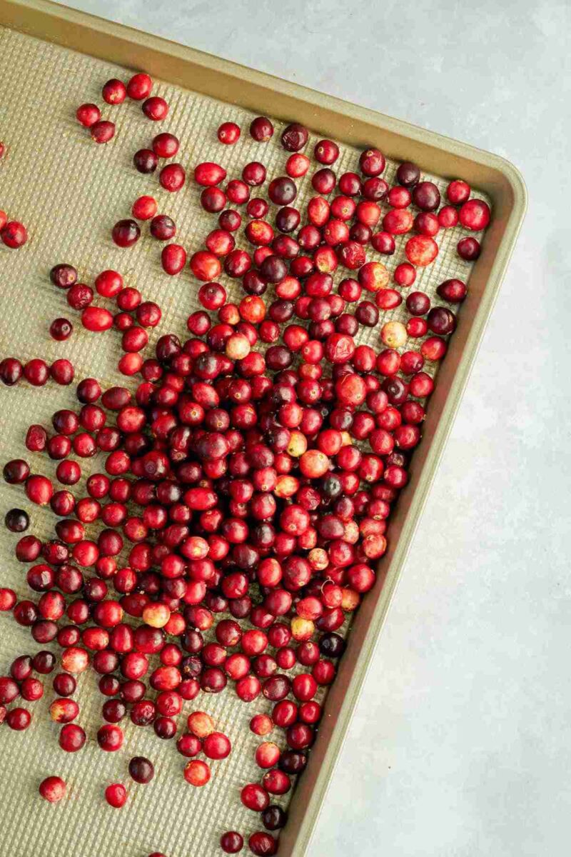 Cranberries on a gold baking sheet.