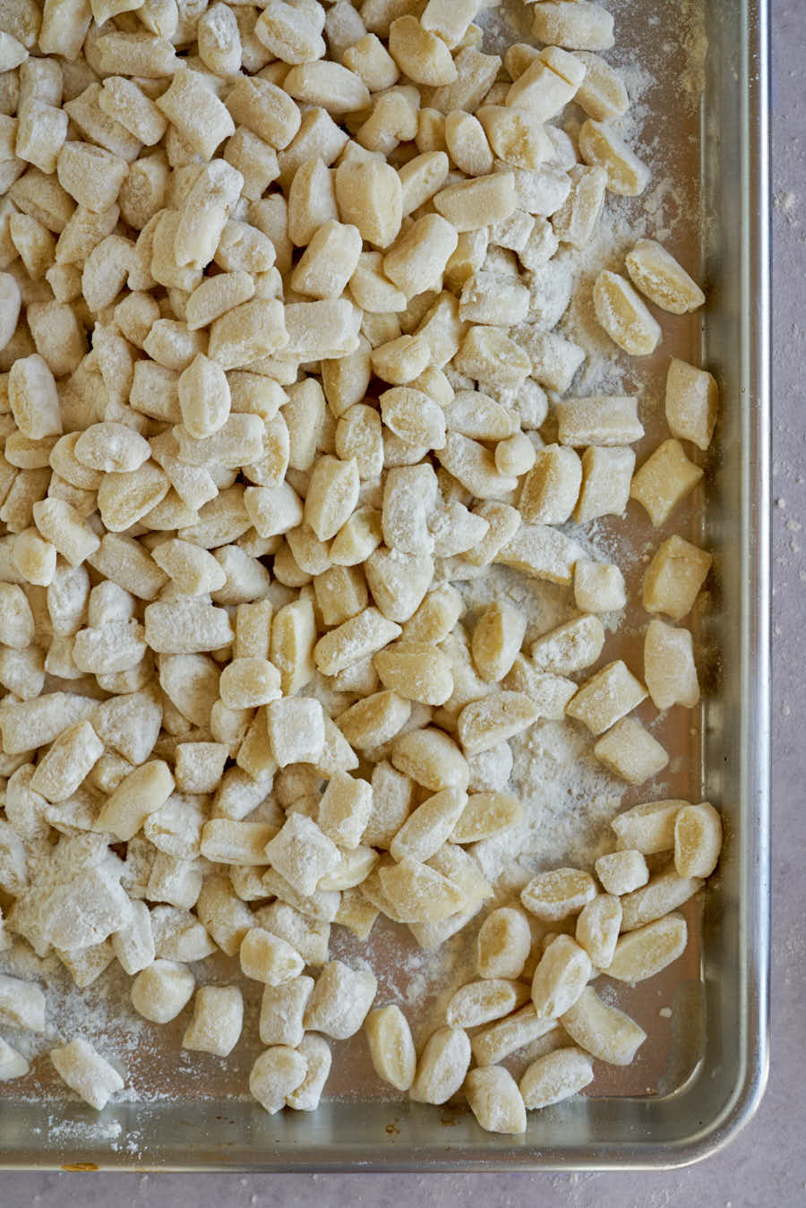 Sheet pan covered with raw gnocchi.