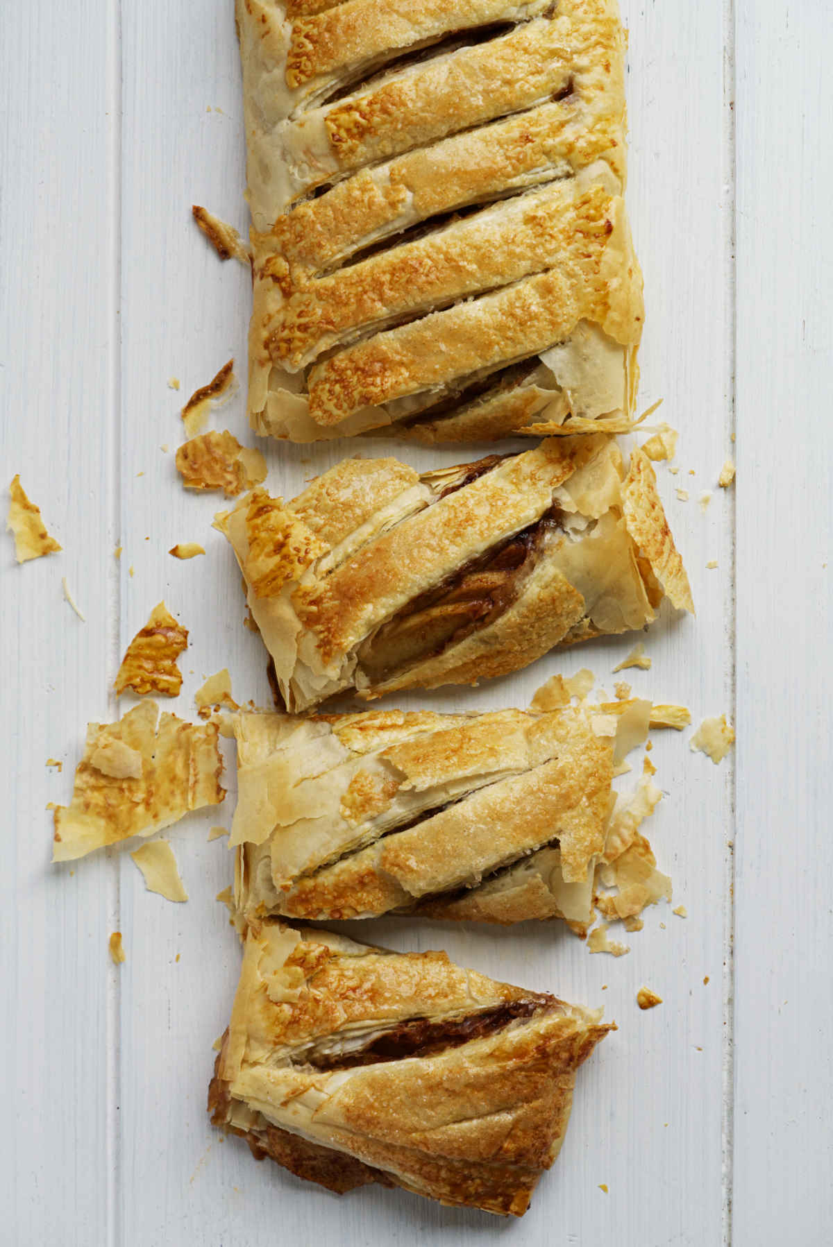 Apple pastry cut up on a white table.