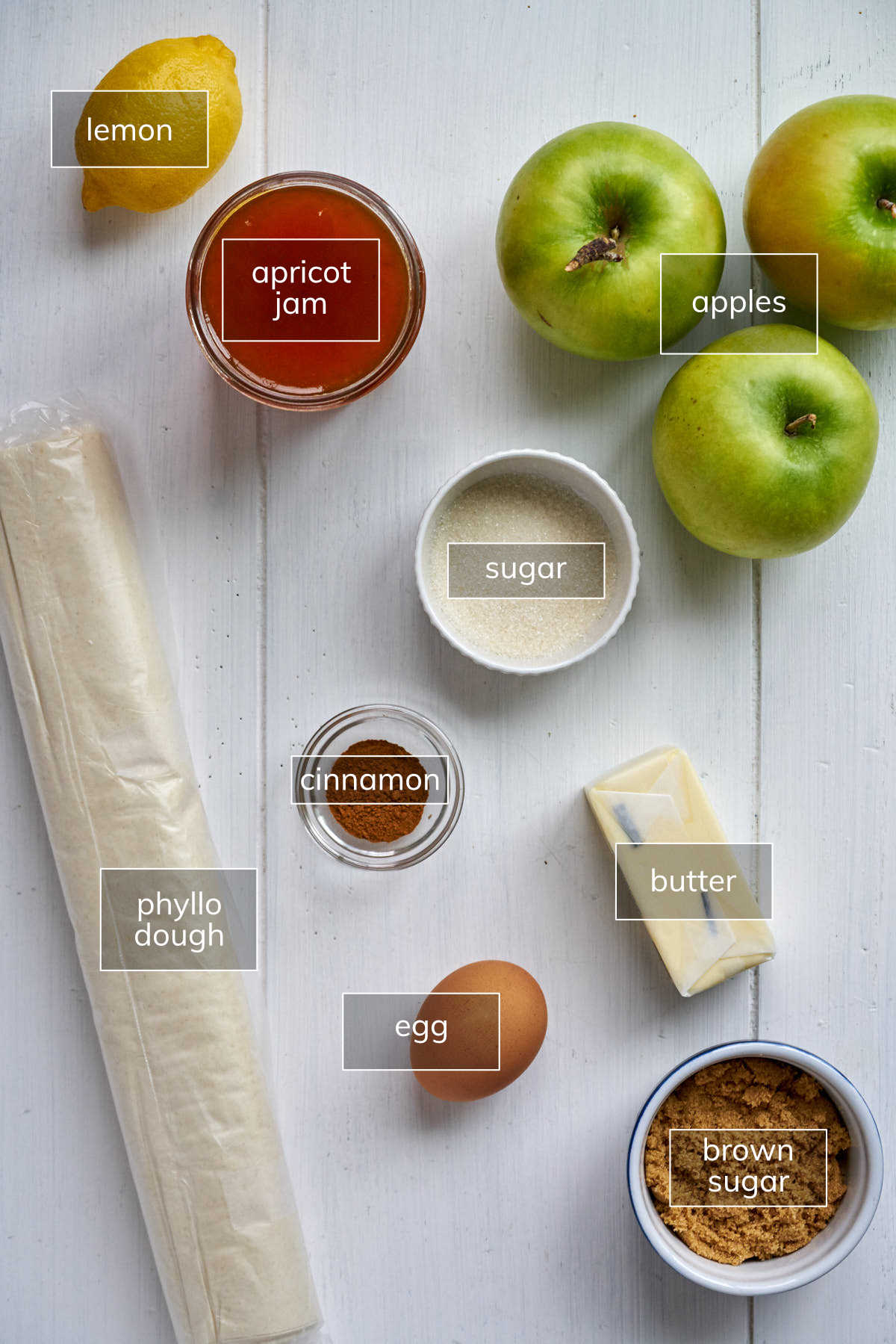 Multiple ingredients for apple strudel on white table.