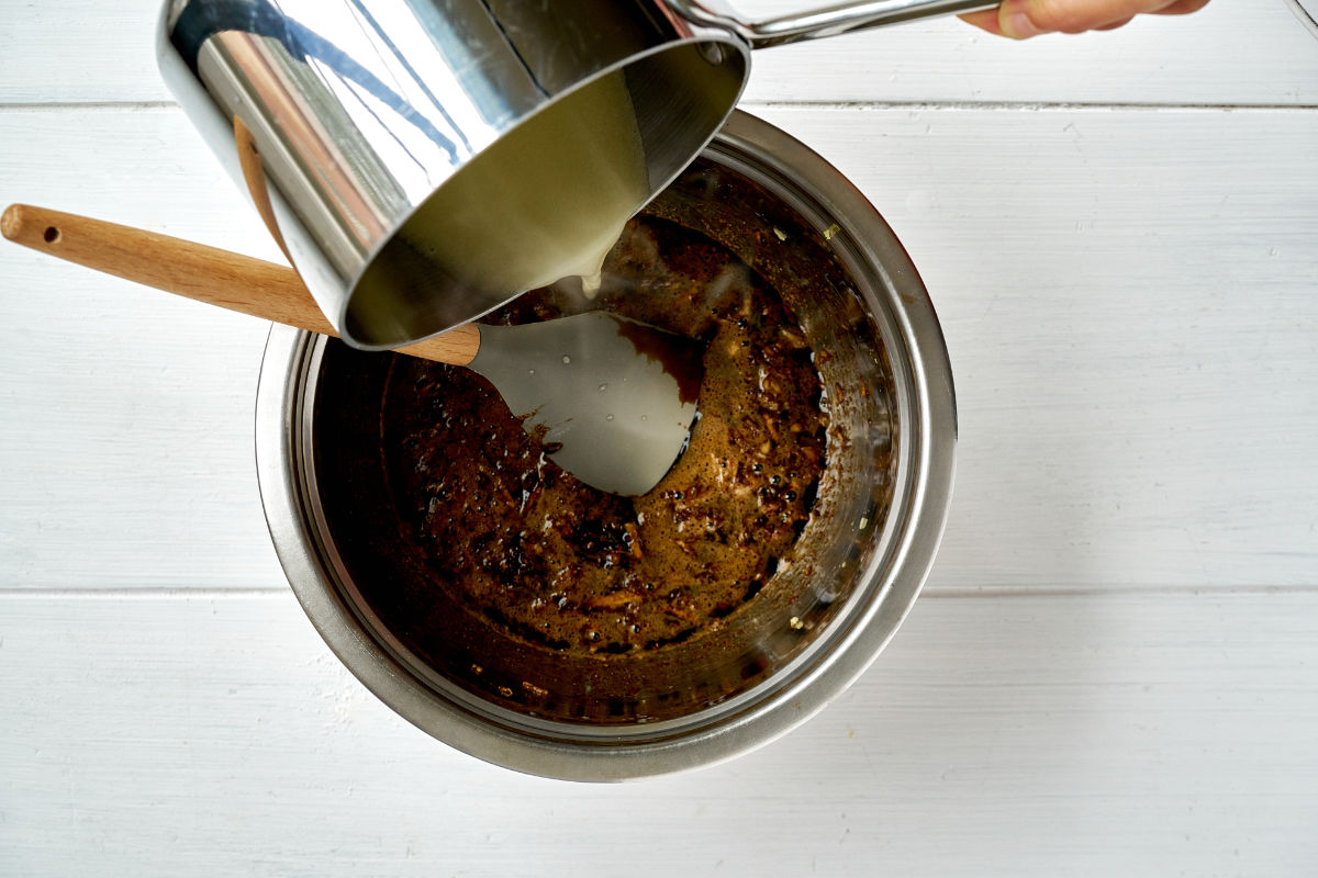 Pouring melted butter into liquid cake batter.
