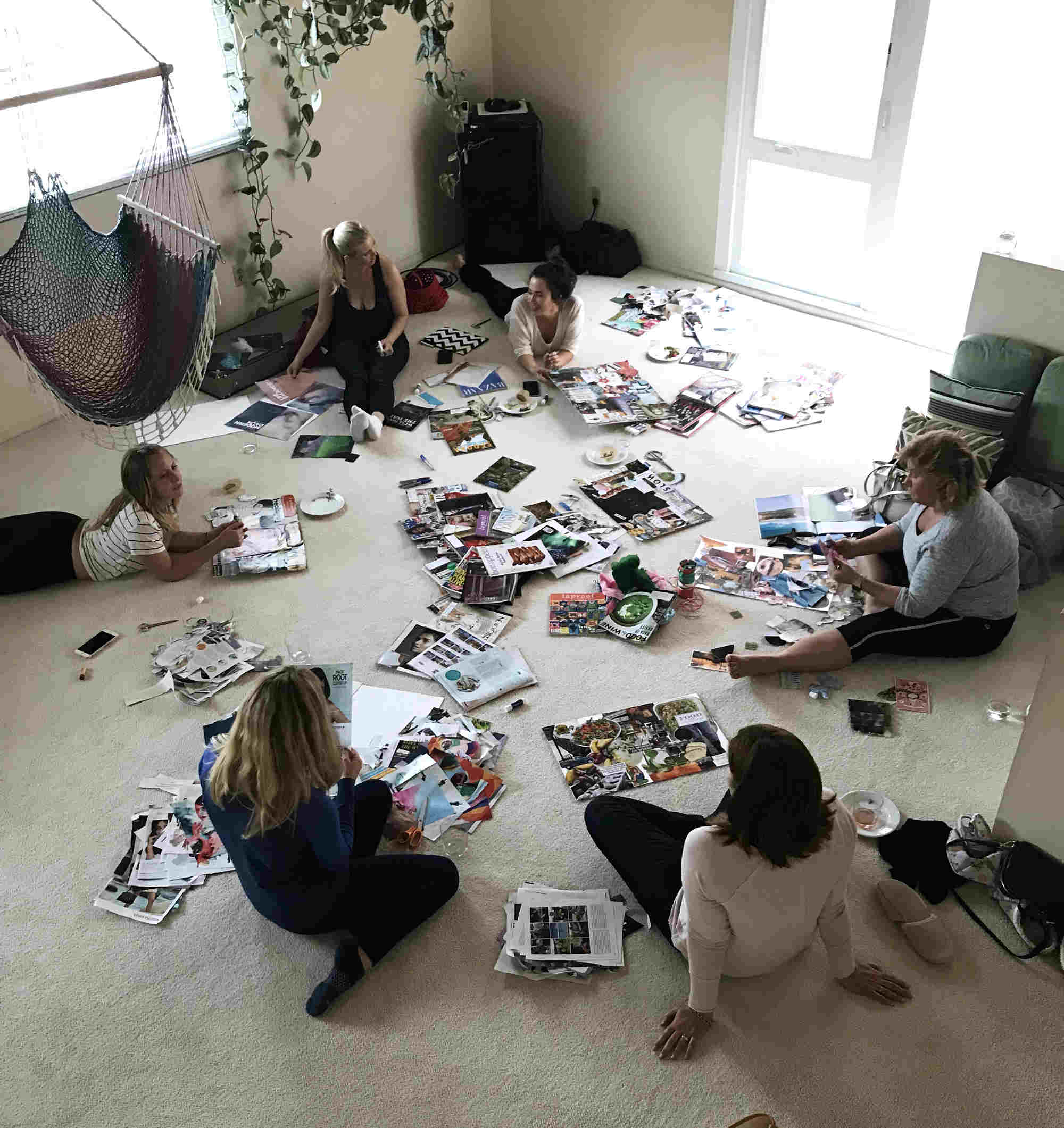 People on the floor of a room with magazines and crafts.