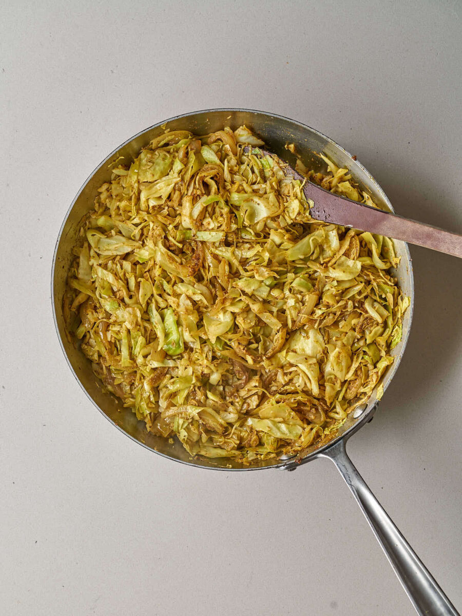 Sautéed shredded cabbage and onions seasoned with shawarma spices in a metal skillet.