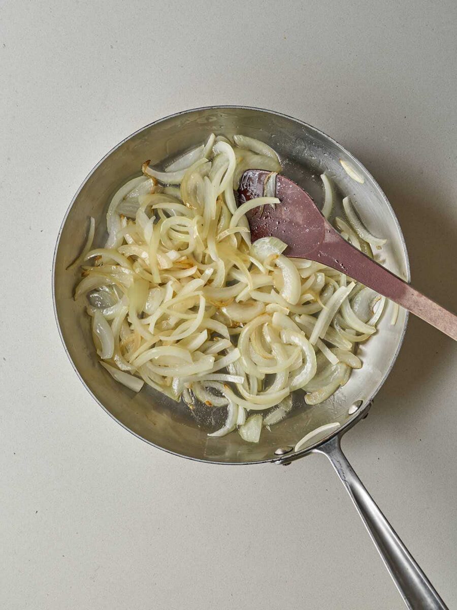 Sautéed, translucent sliced onions in a metal skillet.