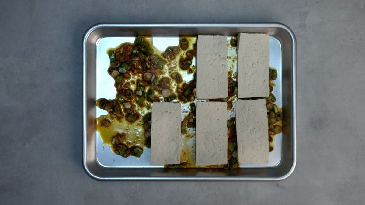Tofu and marinade in a sheet pan.