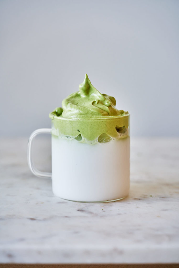 Cup filled half way with coconut milk and topped with matcha foam.