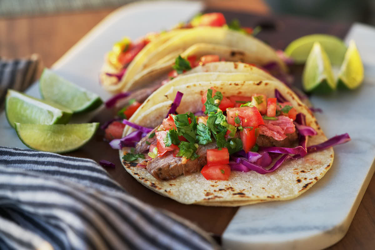 Open faced steak taco with tomatoes and cabbage.