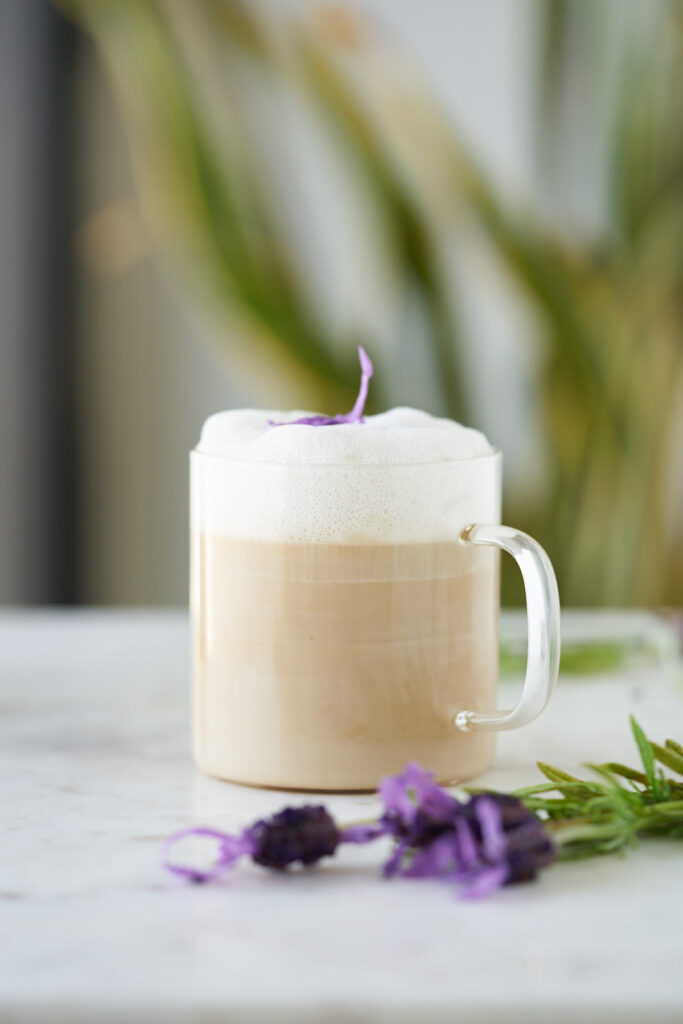 Cup of tea latte topped with a lavender flower.