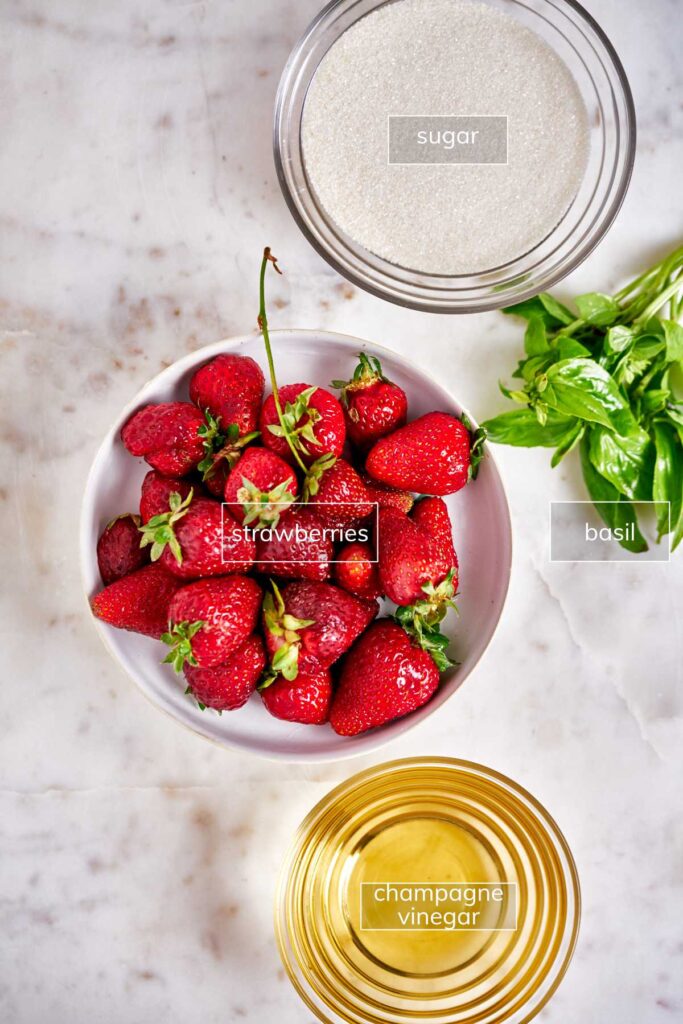 Ingredients for strawberry shrub including strawberries, sugar, basil, and champagne vinegar.