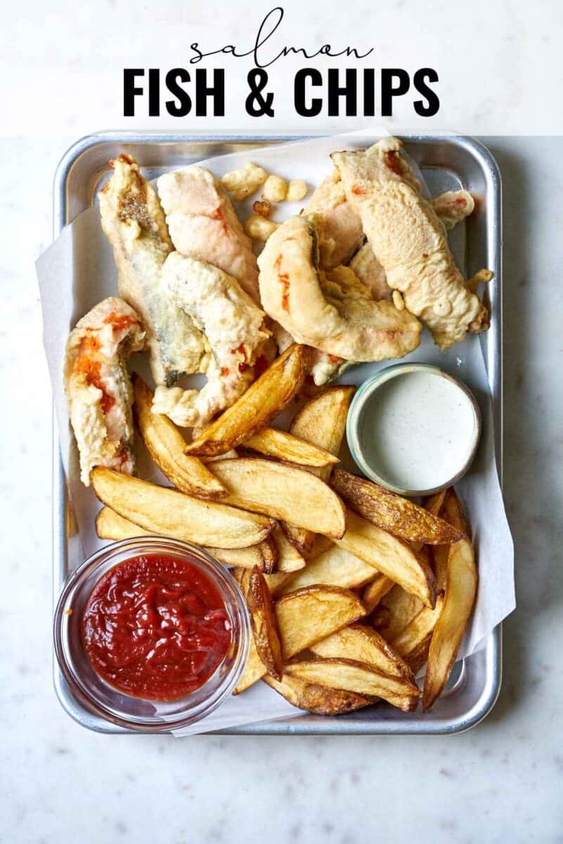 Fried fish on a baking sheet with fries and ketchup.