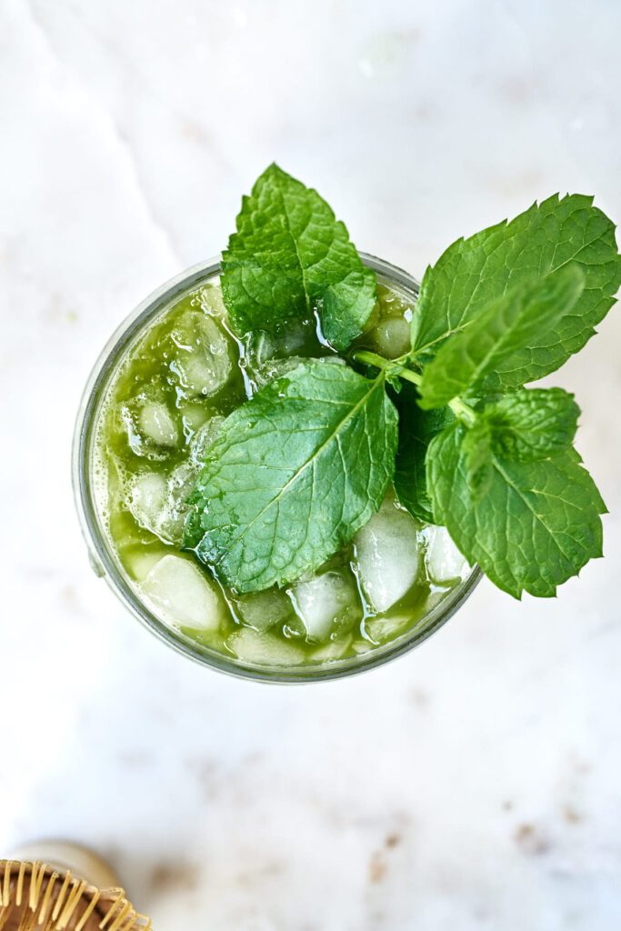 Top view of a matcha cocktail filled with crushed ice and garnished with a sprig of mint.