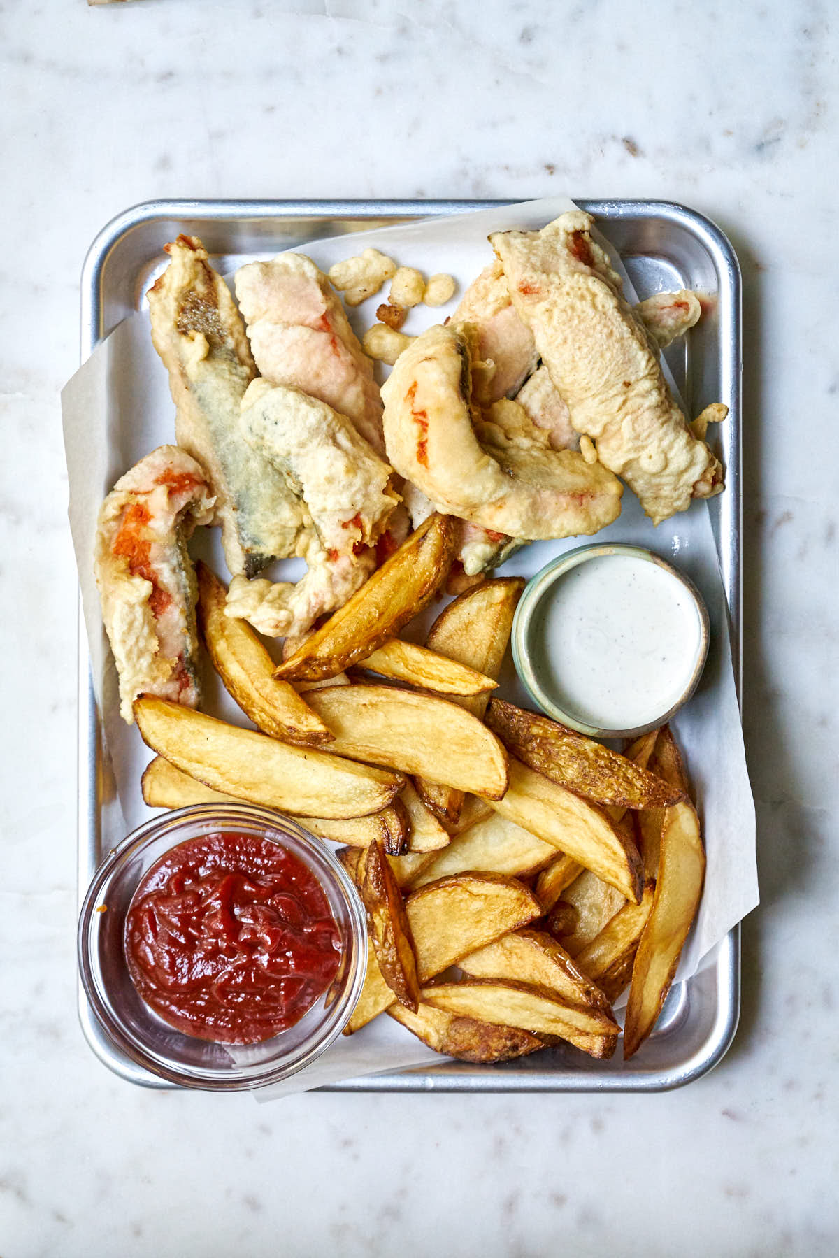 Fish and chips on a tray with tartar and ketchup.