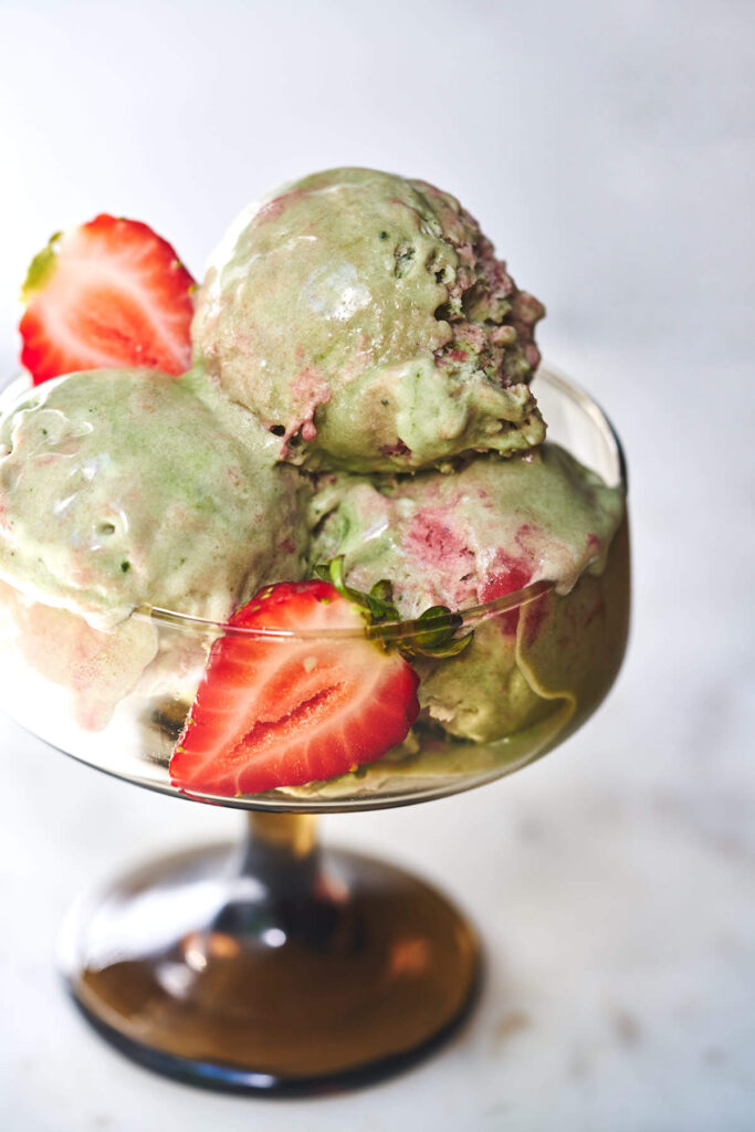 Green tea semifreddo with strawberries in a pedestal glass.