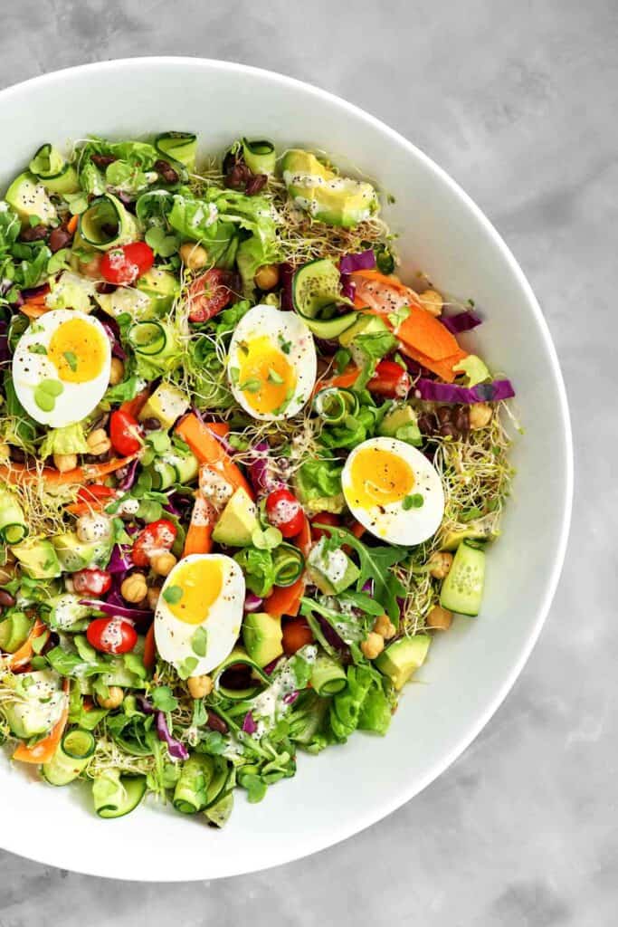 Top view of a meal salad with jammy eggs and poppyseed dressing.