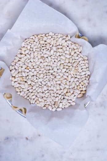 Baking. beans in a pie dish covered in parchment paper.