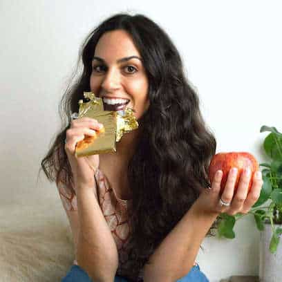 Girl eating chocolate bar and holding an apple.