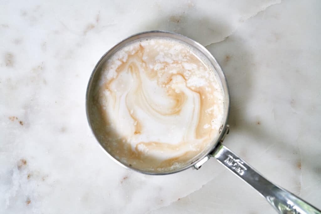 Milk in a measuring cup swirled with tea.