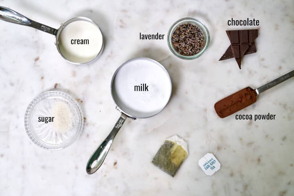 Ingredients for Earl Grey hot chocolate and lavender whipped cream on a white countertop.