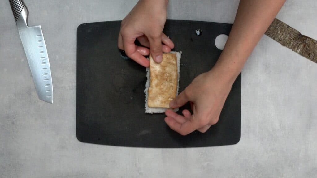 Placing tofu on top of rice.