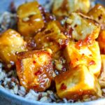Sticky tofu in a ceramic bowl with brown rice.