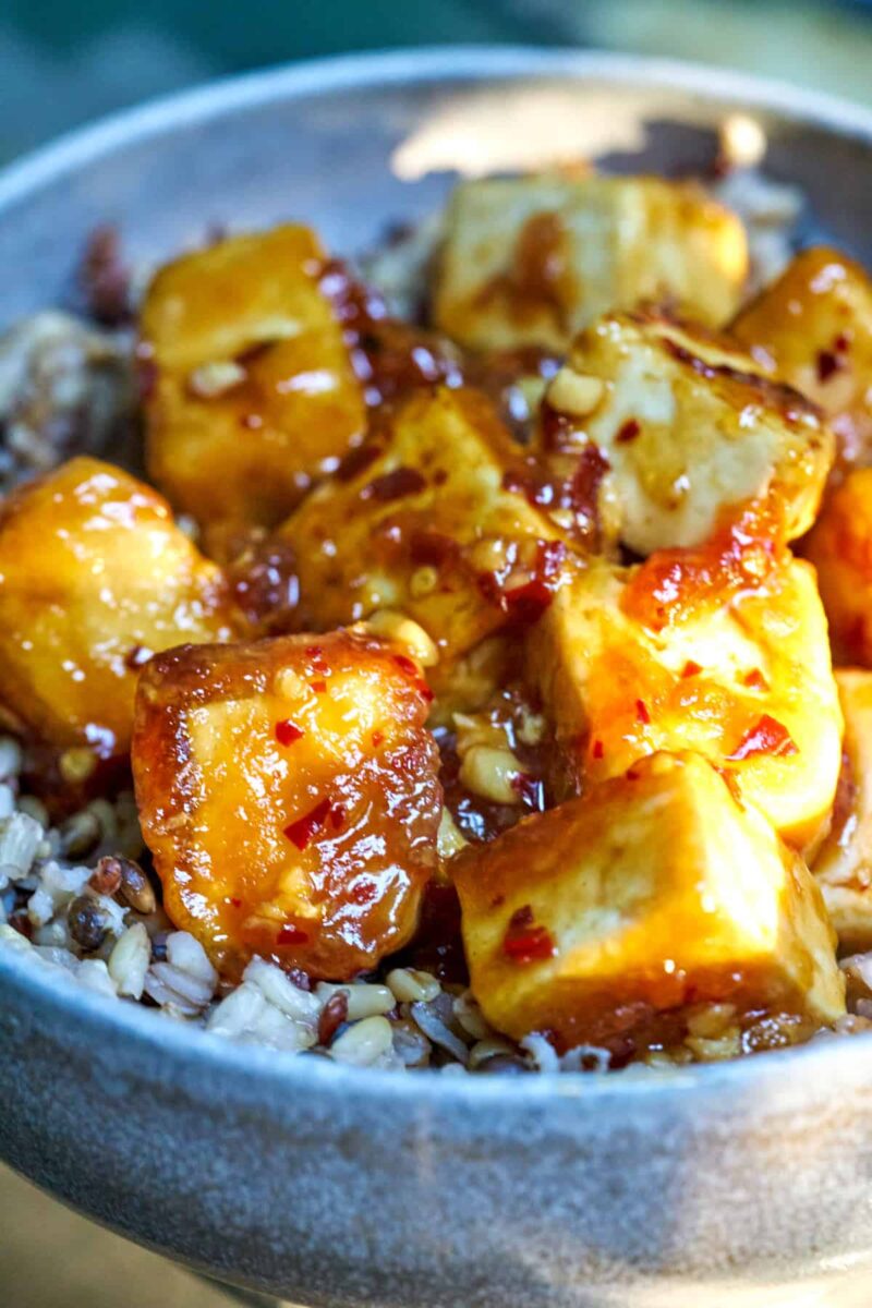 Sticky tofu in a ceramic bowl with brown rice.